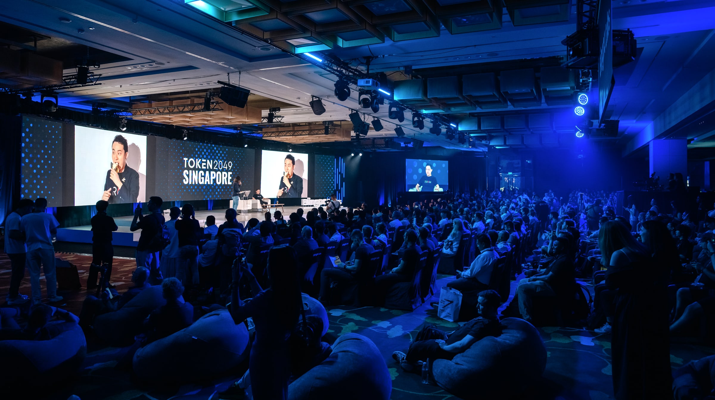 The 2025 roast — the main stage at Token2049 Singapore, TOKEN2049 screens flanking, the hall packed to the walls